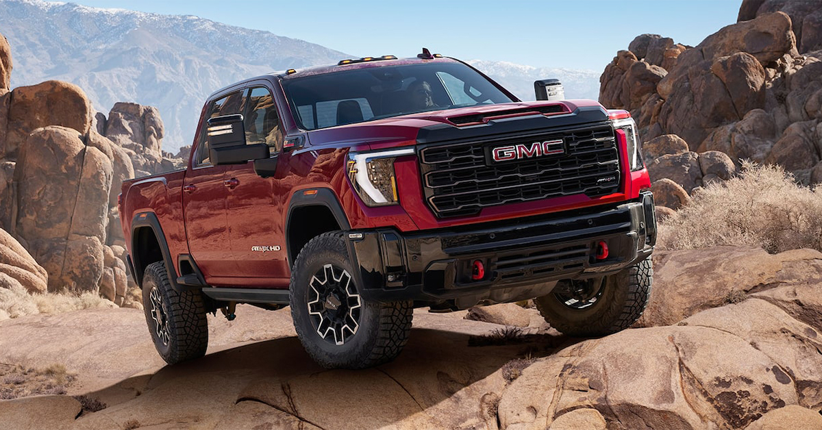 2025 GMC Sierra 2500 heavy duty truck with wide mirrors driving over a rocky hill